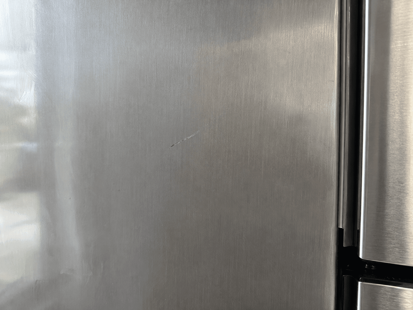 Illustration of a small cosmetic scratch on a brushed stainless steel refrigerator panel